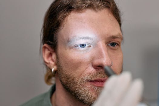 A close-up image of a young man undergoing an eye examination by a medical professional.