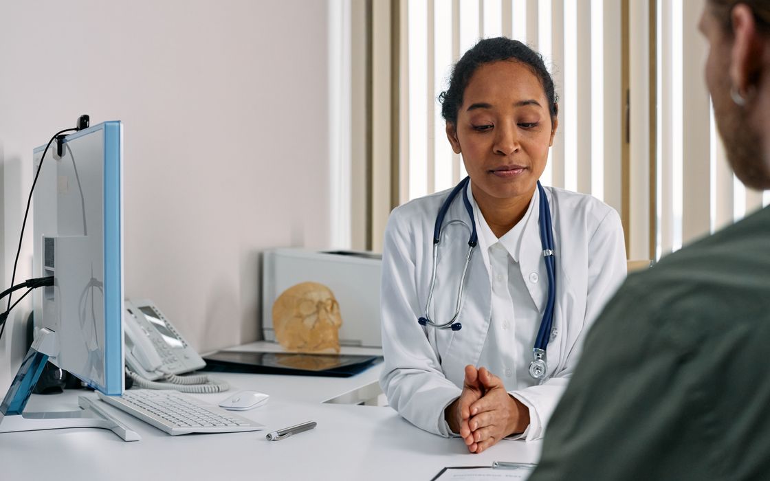 Doctor in a white coat listening to a patient during a consultation in a modern clinic office