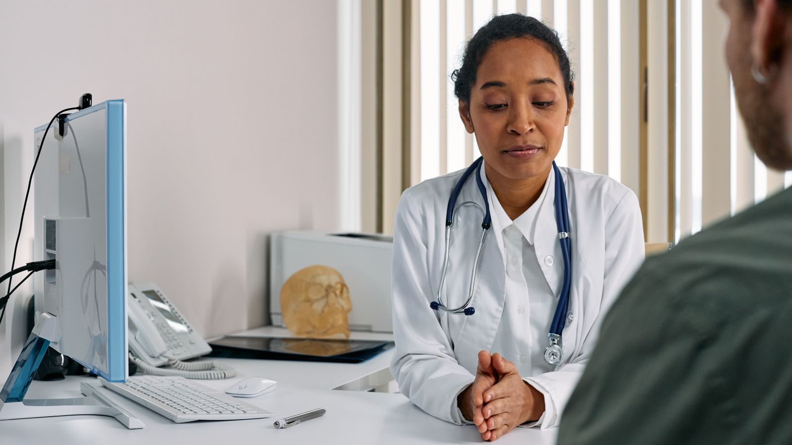 A female doctor consulting a patient in a modern medical office setting.