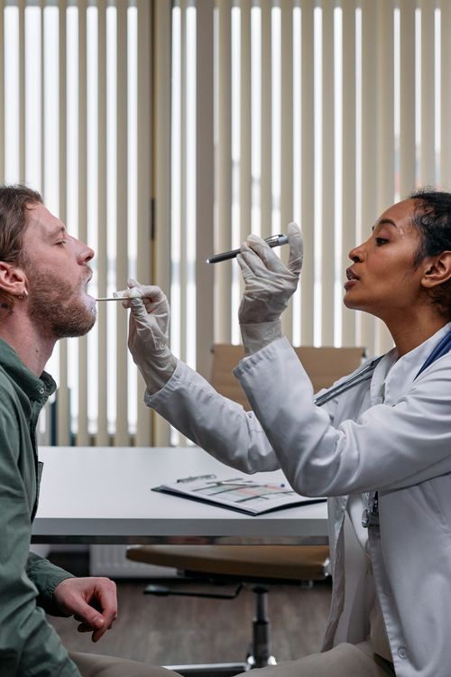 Free A doctor examines a patient by checking his throat in a clinical setting. Stock Photo