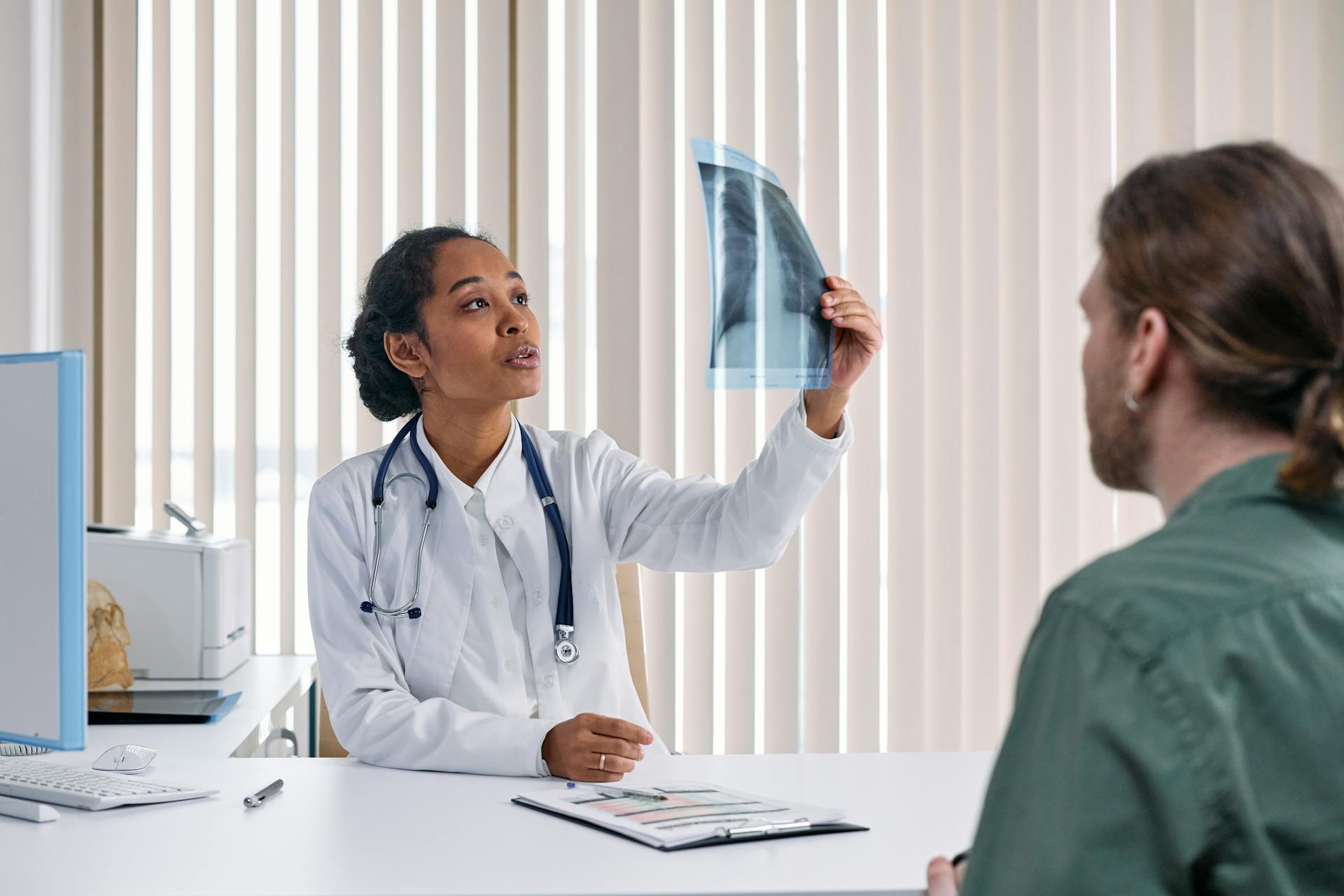 Woman in White Suit with Stethoscope Looking at X-ray Result