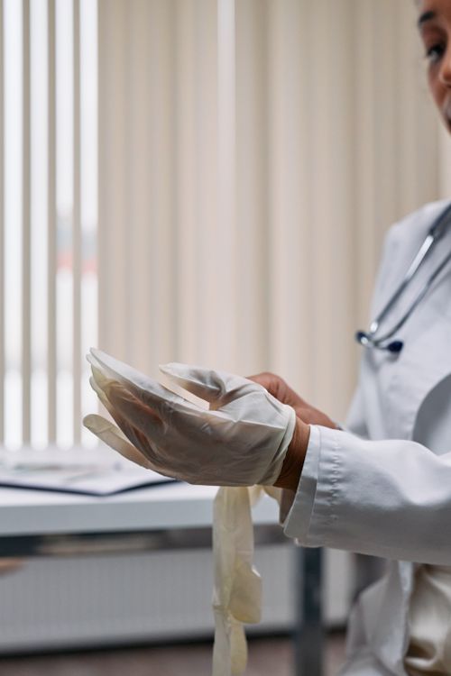 Free A healthcare professional putting on latex gloves in an office setting. Stock Photo