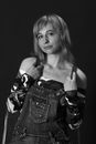 Black and white of attractive female model in long sleeve camouflage off shoulder t shirt and overall looking at camera on black background