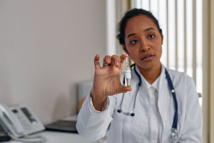 Woman In White Suit Holding Clear Glass Ampoule