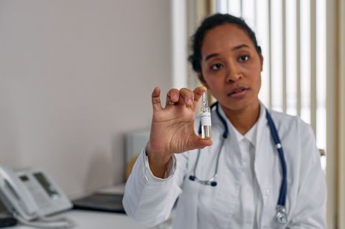 Free A female doctor in a white coat holding a medical ampoule, illustrating healthcare professionalism. Stock Photo
