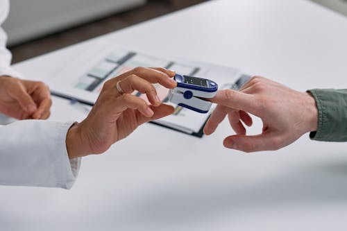 Close-up of Doctor Putting a Fingertip Pulse Oximeter on a Patients Finger 