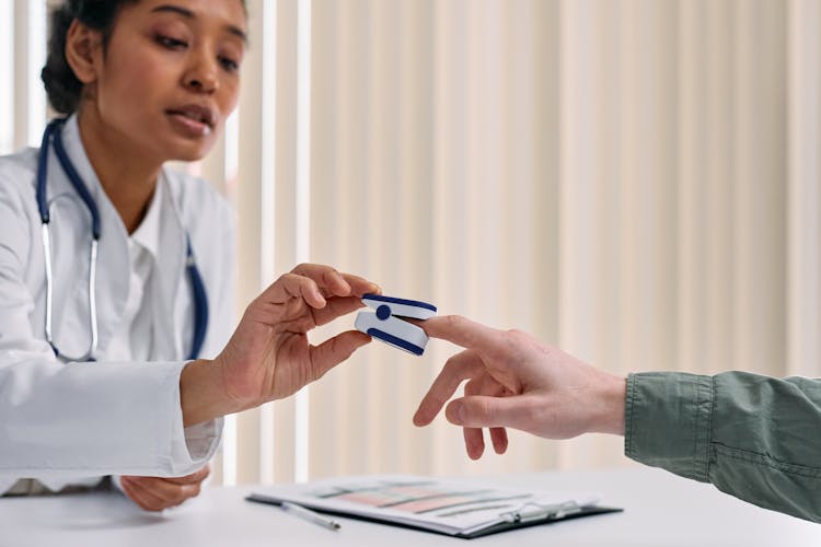 Woman Putting Pulse Oximeter On Man