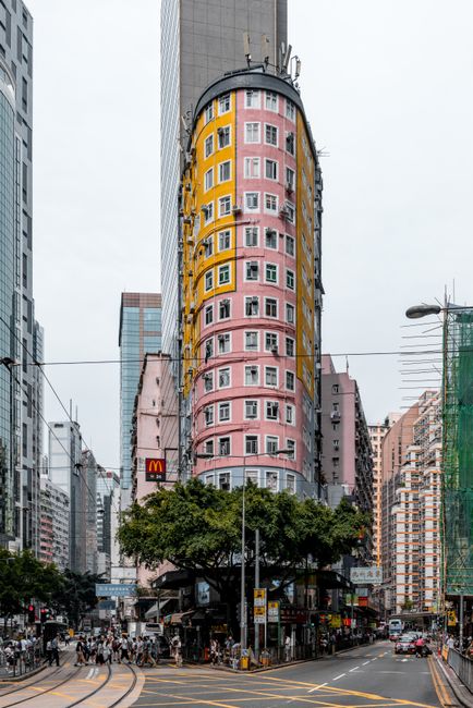 Vivid pink and yellow building amidst a busy urban street scene capturing vibrant city life.