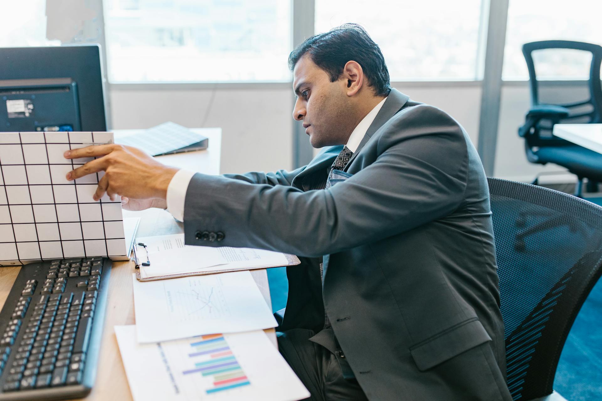 A businessman in a suit reviewing data charts at his office desk.