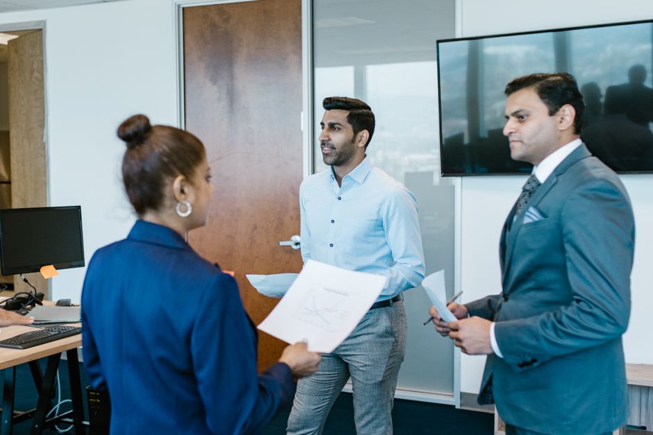 the role of soft skills in digital leadership - Professional team in a modern office discussing work documents during a meeting.