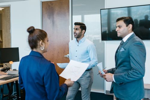 Free Professional team in a modern office discussing work documents during a meeting. Stock Photo
