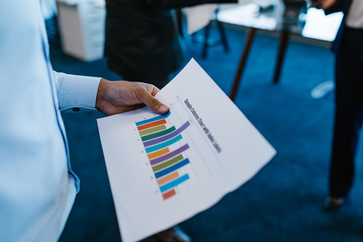 A person holding a printed bar chart comparing several results