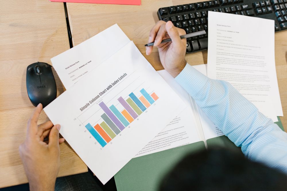 An analyst reviewing printed charts and documents at a desk.
