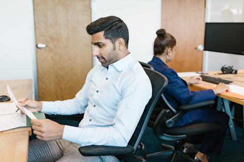 Man in Blue Dress Shirt Sitting on Black Chair