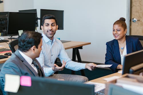 Man in Blue Dress Shirt Sitting Beside Man in Black Suit