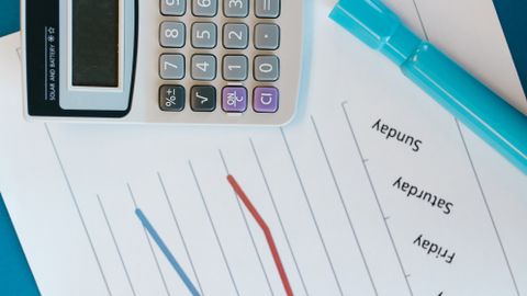 Top view of office desk with calculator, graph papers, and a marker.
