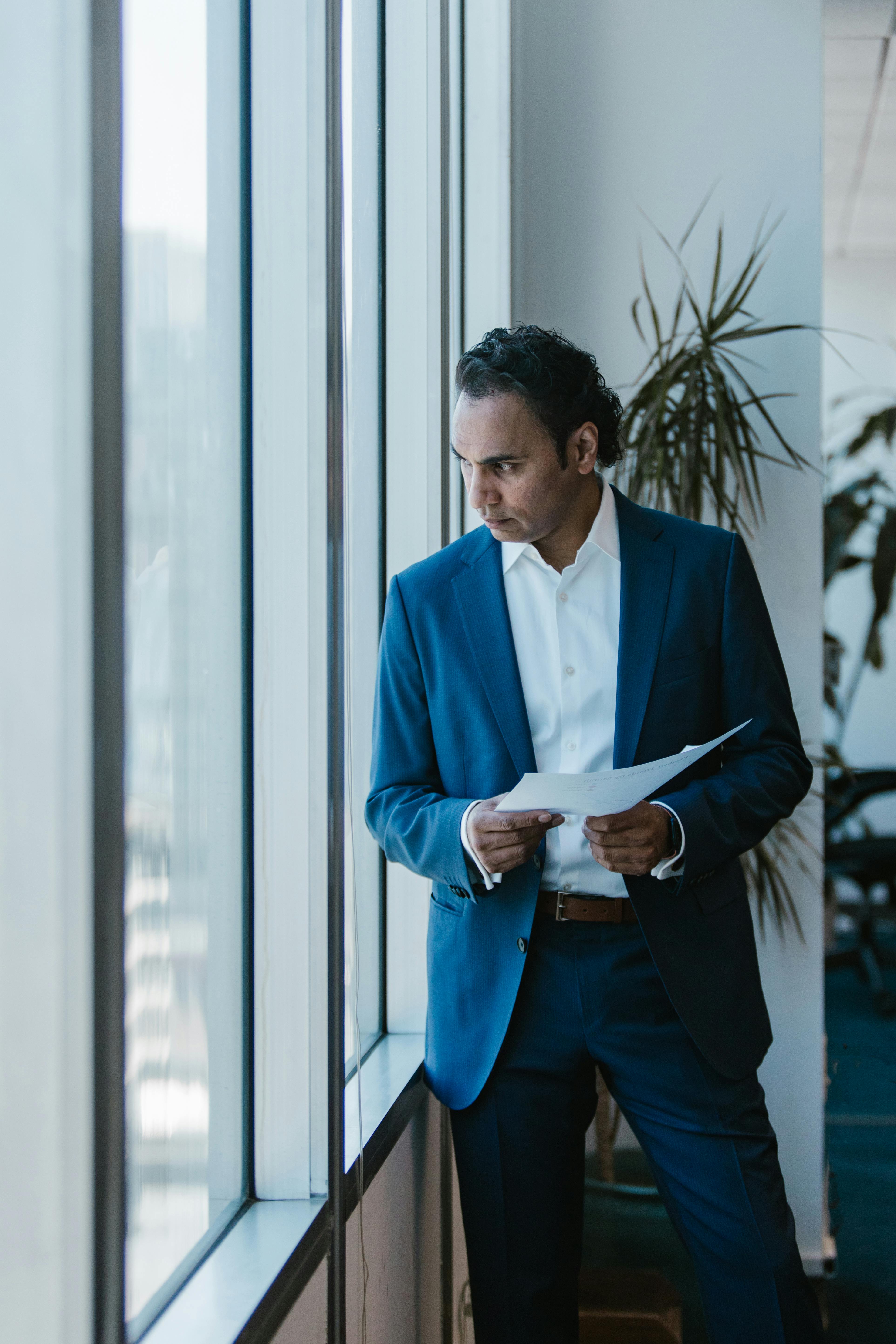 Man in Blue Suit Standing Near White Wall