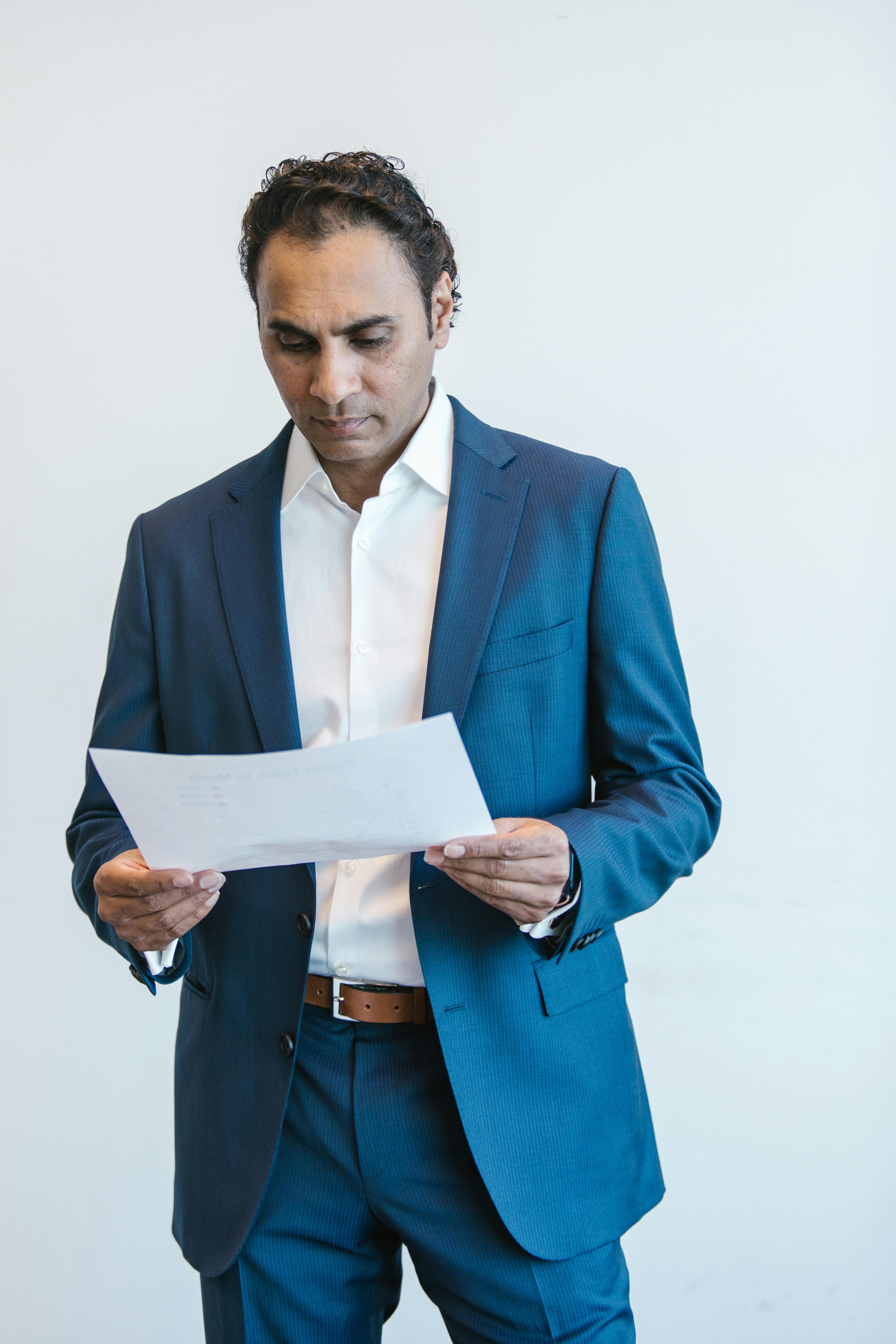 Man in Blue Suit Holding White Paper