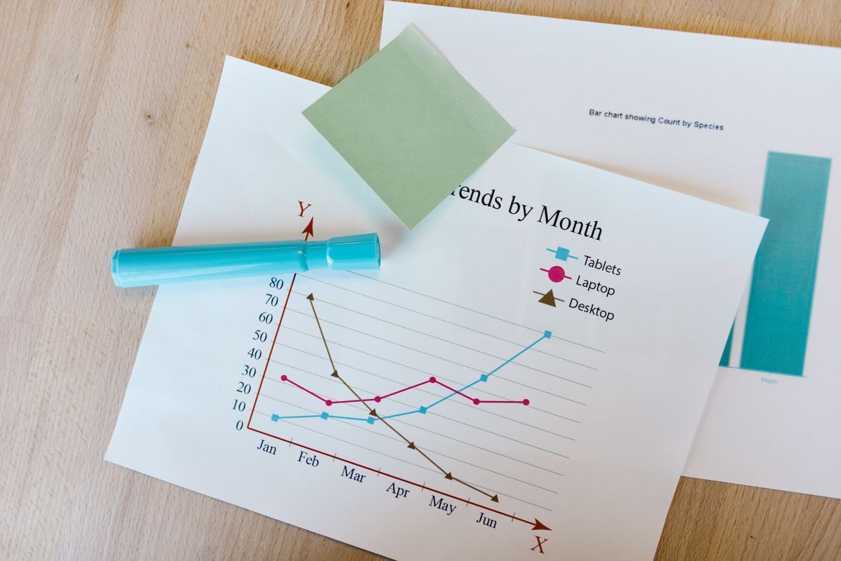 Two people comparing charts and visual materials on a desk, illustrating a side-by-side tool comparison