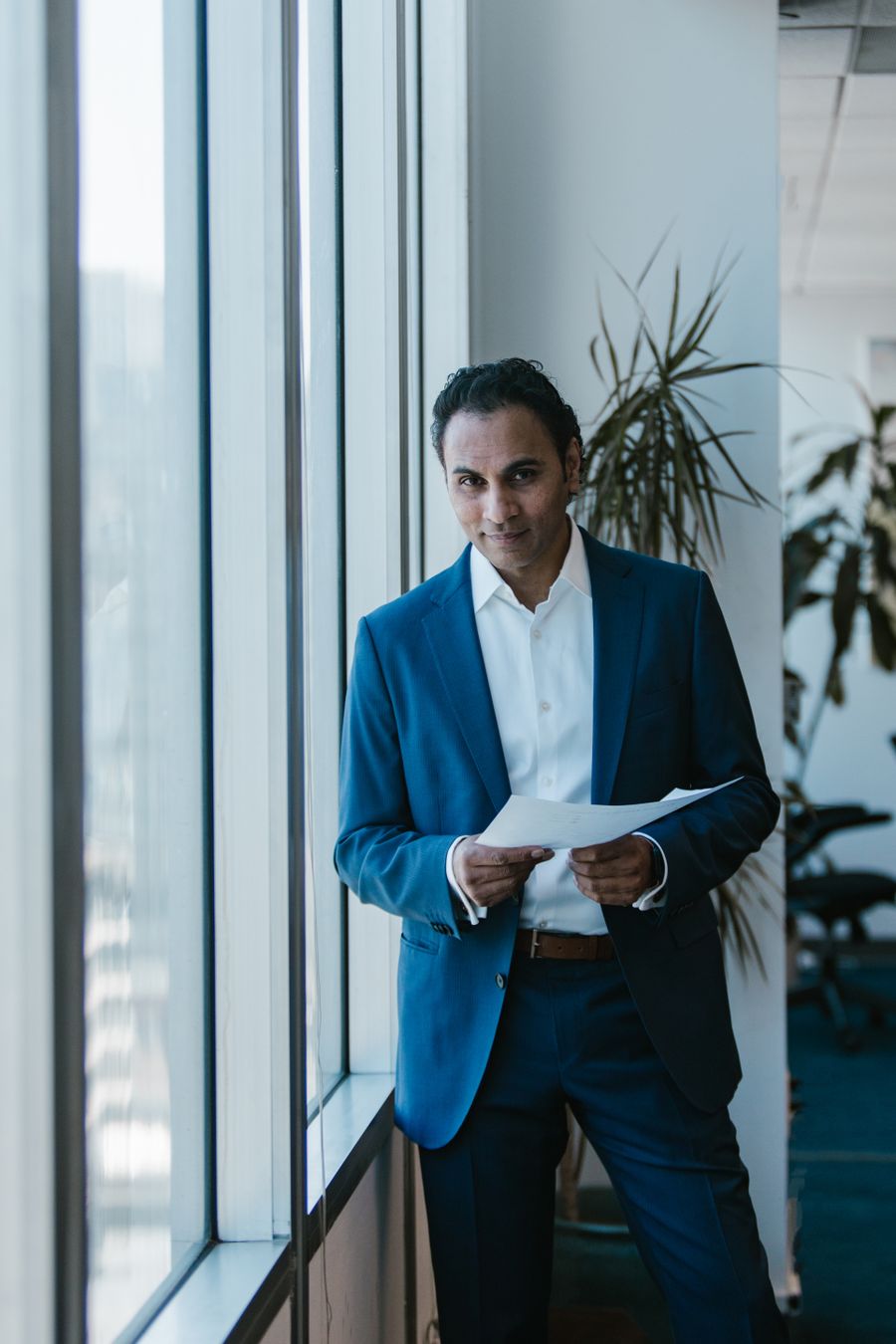 Indian consultant holding a report beside an office window