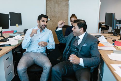 Free Team discussing project with enthusiasm at office desks, fostering collaboration. Stock Photo
