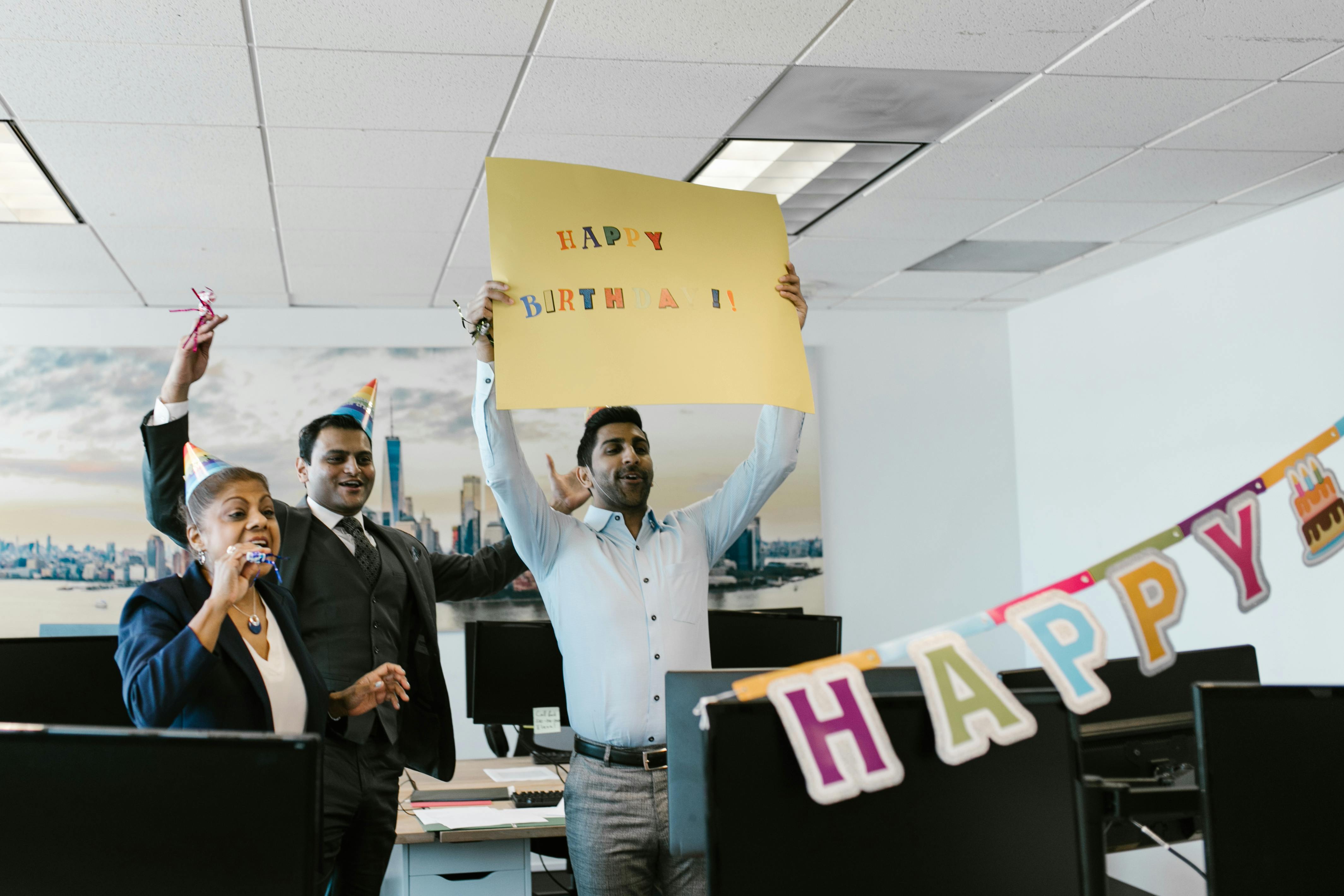 A joyful office birthday celebration with colleagues holding a sign. Perfect for business and lifestyle concepts.
