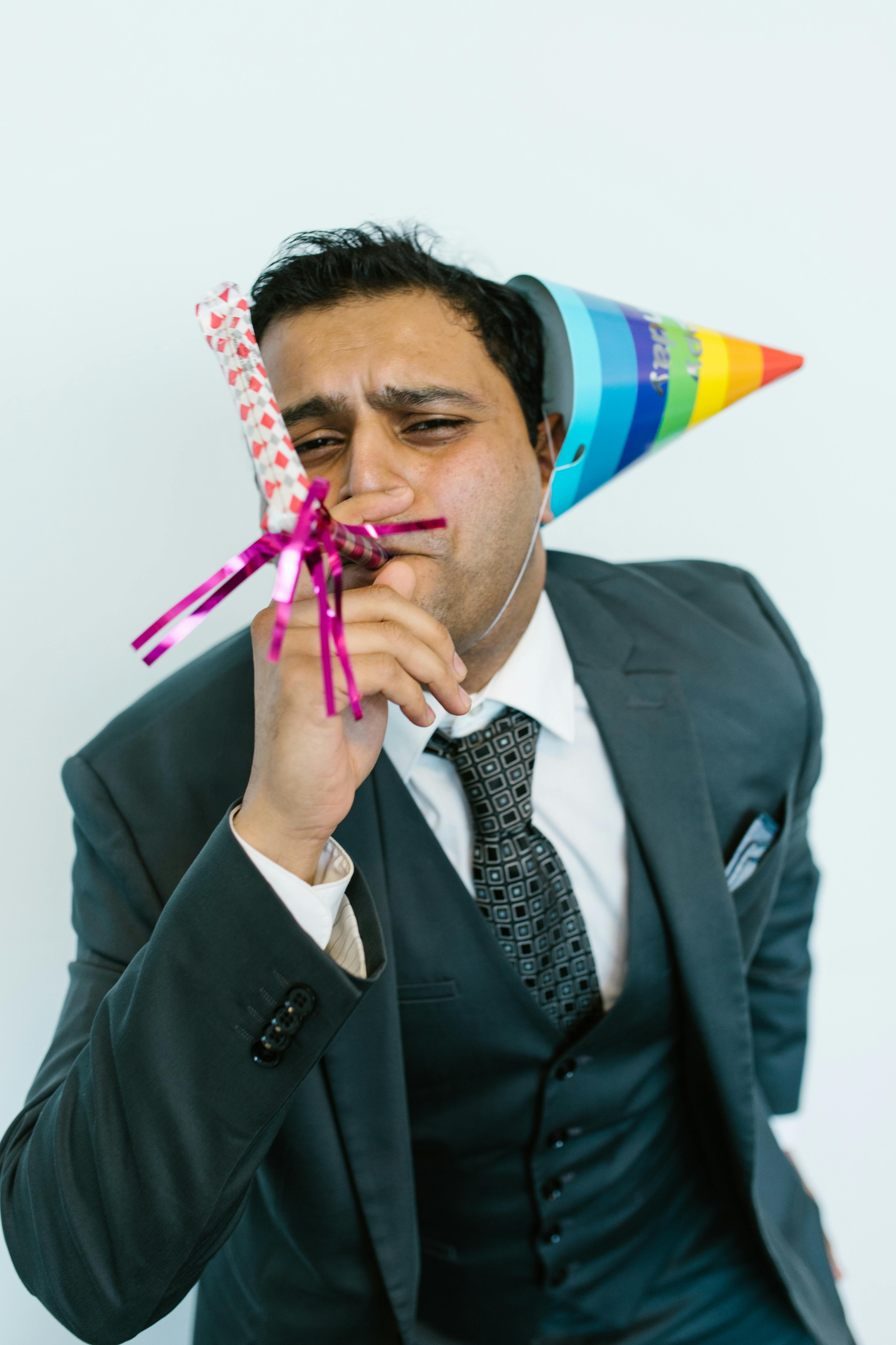 Man in Black Suit Jacket With Purple Yellow and Blue Ribbon on His Head