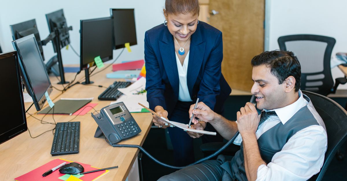 Business professionals discussing documents in a modern office setting.