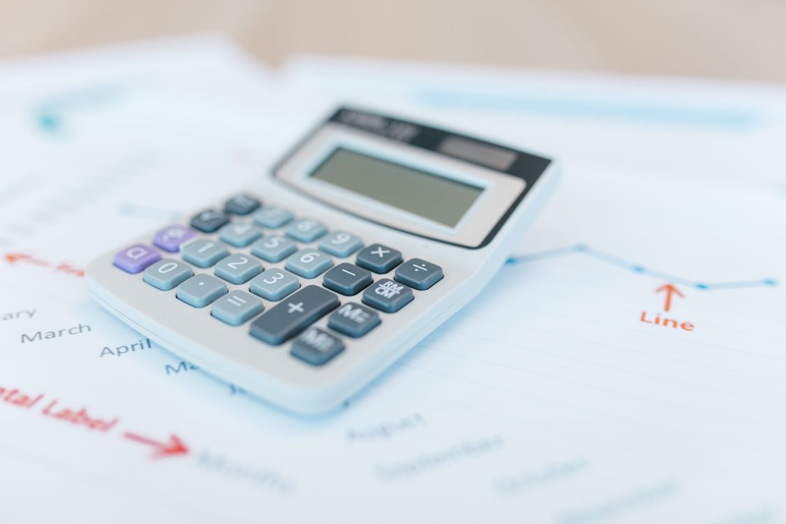 Calculator resting on top of financial analysis documents with charts