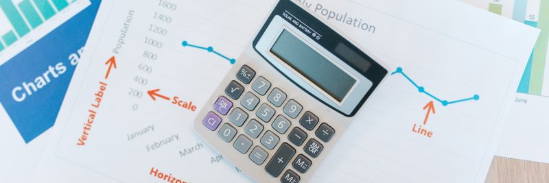 Calculator placed on financial graphs and reports showcasing data analysis and business documentation.