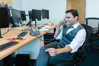 Man in White Dress Shirt and Blue Vest Sitting on Black Office Rolling Chair