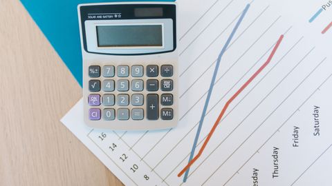 Top view of calculator and graph paper on office desk, perfect for business themed visuals.