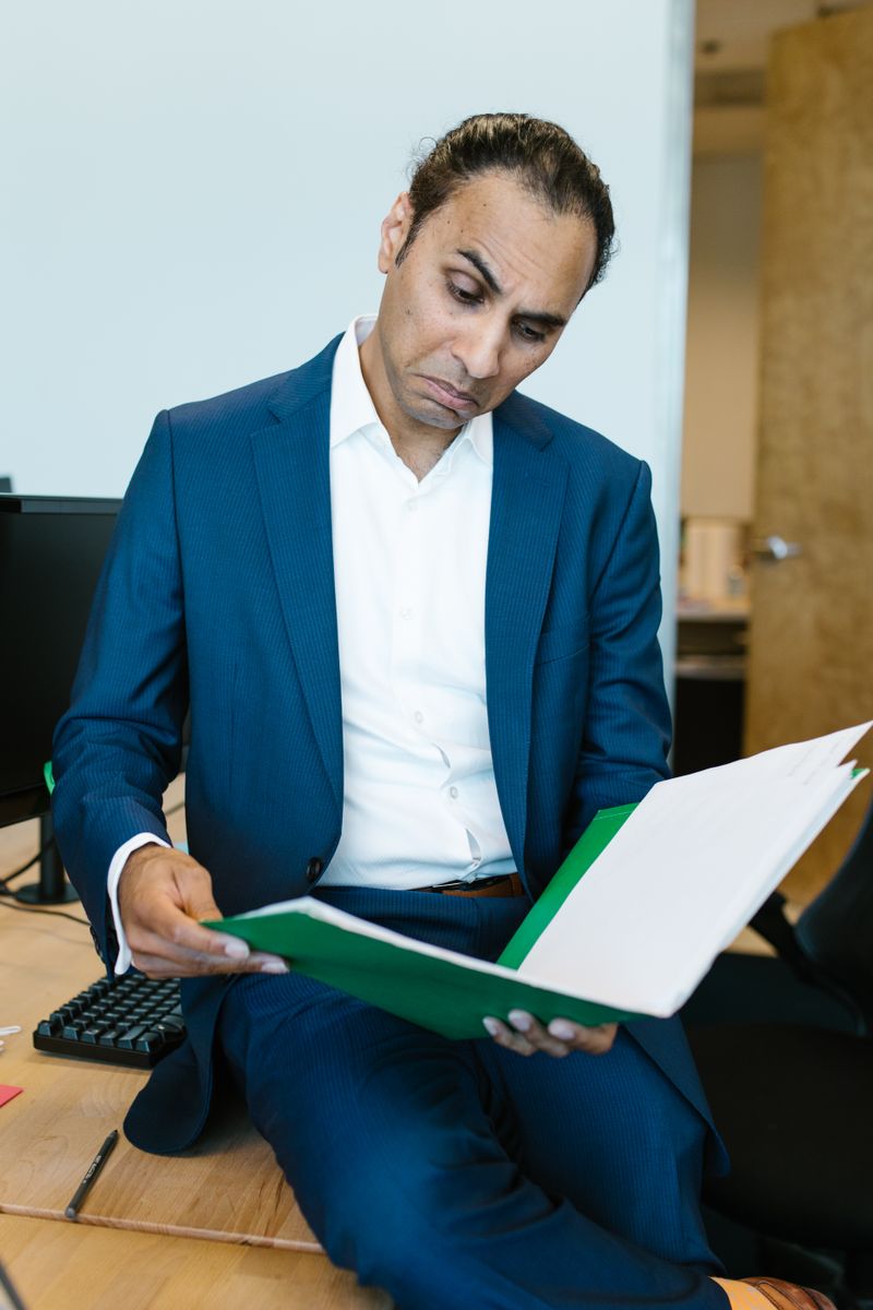 Indian professional in a suit reviewing a compliance document at his desk