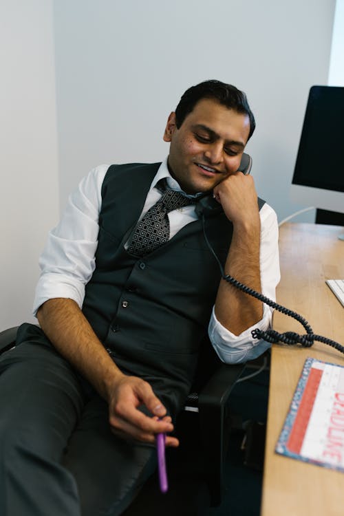 Man in Black Vest and White Dress Shirt Sitting on Black Office Rolling Chair