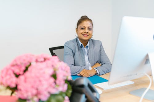 Woman in Blue Dress Shirt Sitting on Black Office Rolling Chair