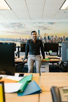 Confident man posing in a contemporary office setting with city skyline backdrop.