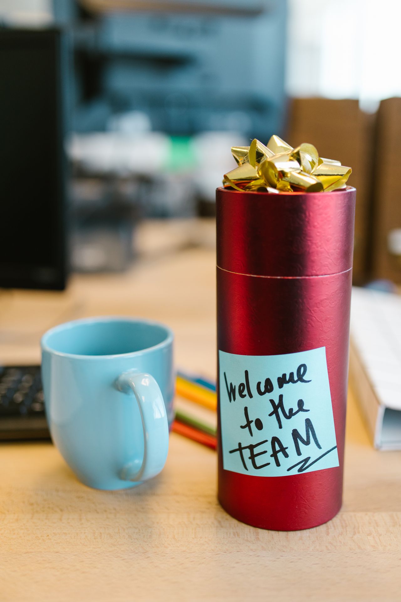 Red gift on desk with Welcome to the Team sticky note
