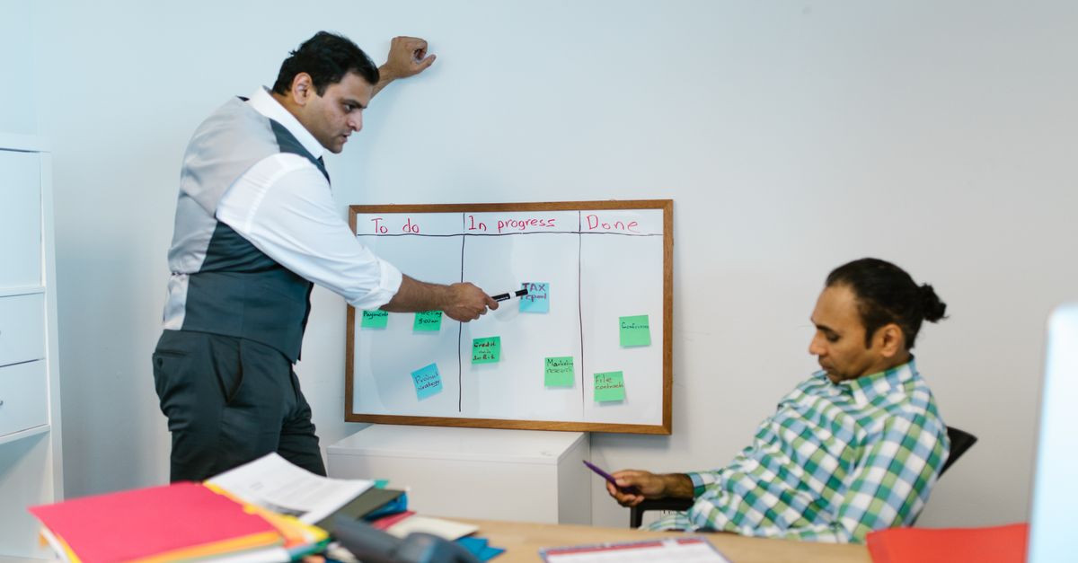 Two men collaborating on a project using a whiteboard in an office setting.