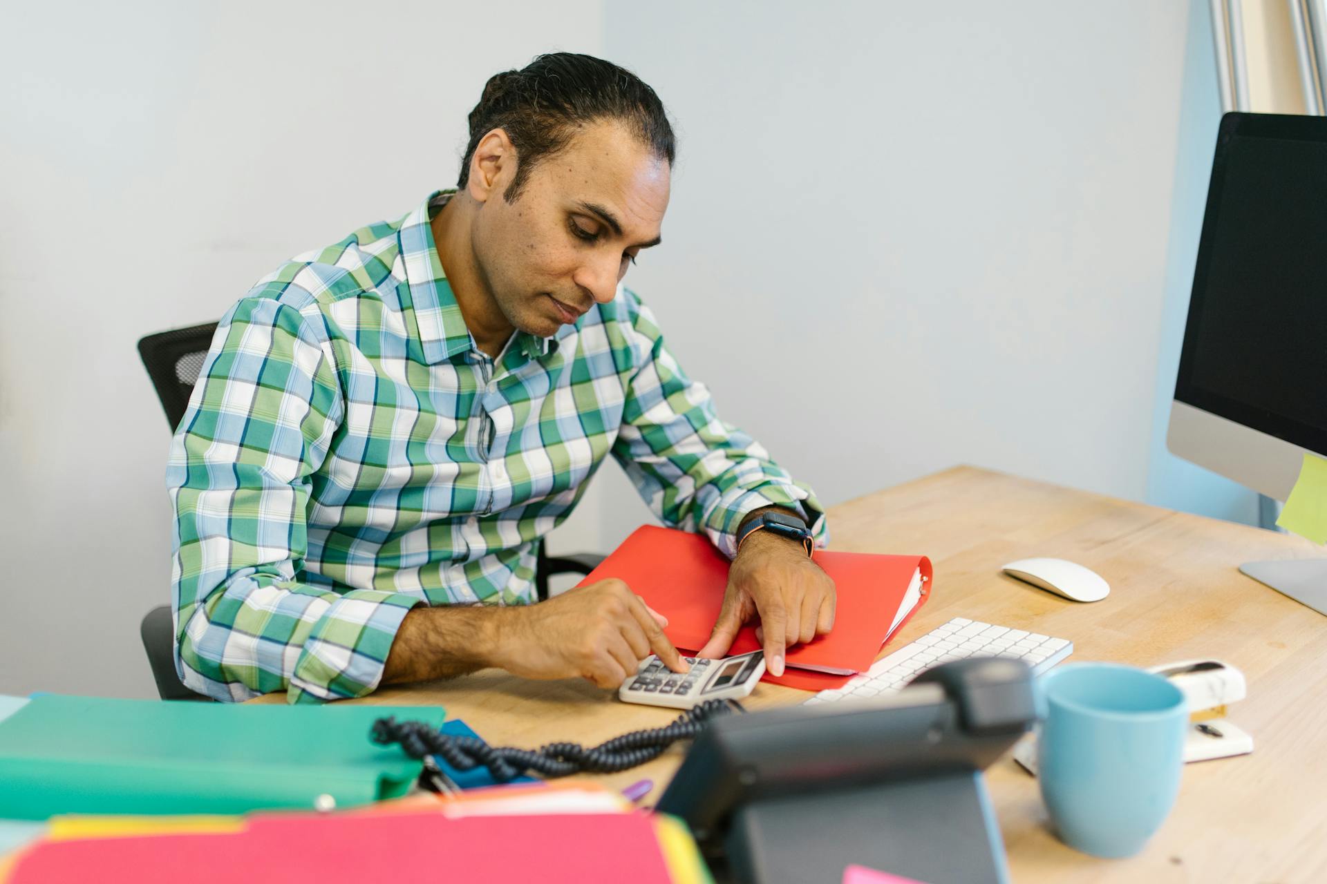 Man engaged in focused calculation work in an office environment.