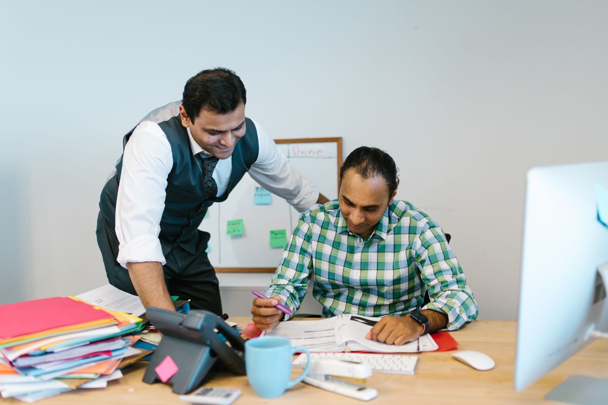 Two Indian hospital administrators reviewing grievance documents together in an office