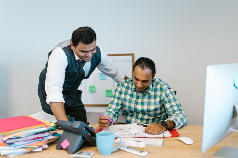 Two Indian hospital administrators reviewing grievance documents together in an office