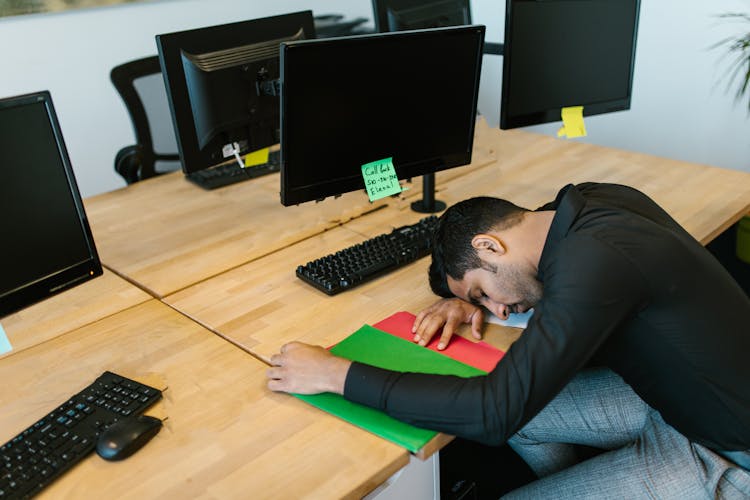 Man In Black Long Sleeve Shirt Sleeping In Front Of A Computer