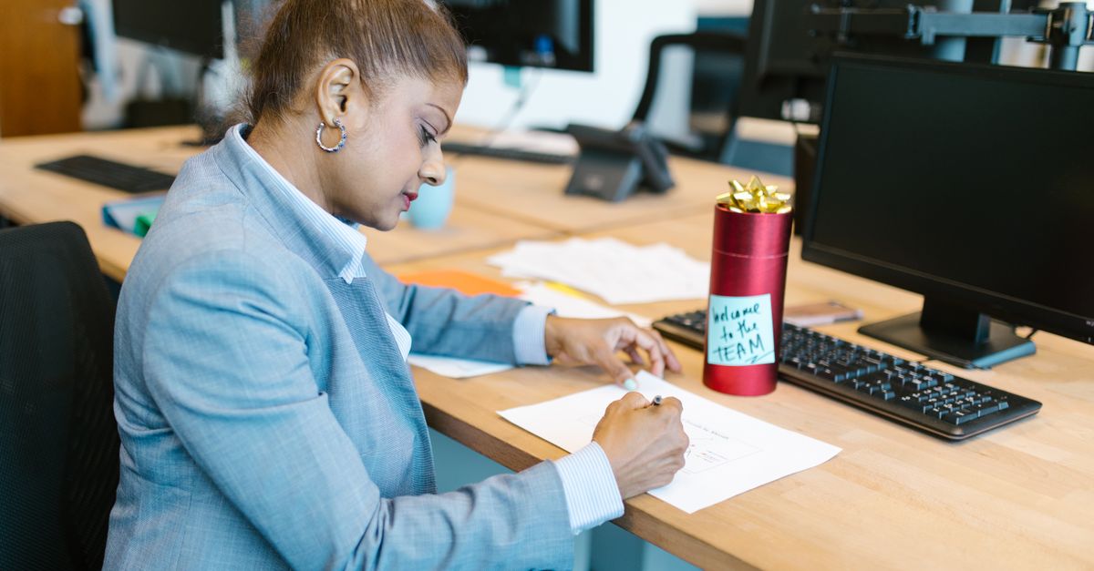 A focused woman working at her desk in a modern office setting with a welcome gift on display.