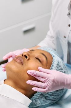 A woman receiving a facial treatment at a spa with a beautician wearing gloves.
