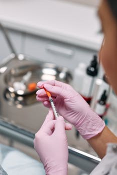 A healthcare worker in gloves prepares an injection in a clinical setting, showcasing medical precision.