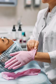 Medical personnel wearing pink gloves preparing for a patient's procedure in a clinical setting.