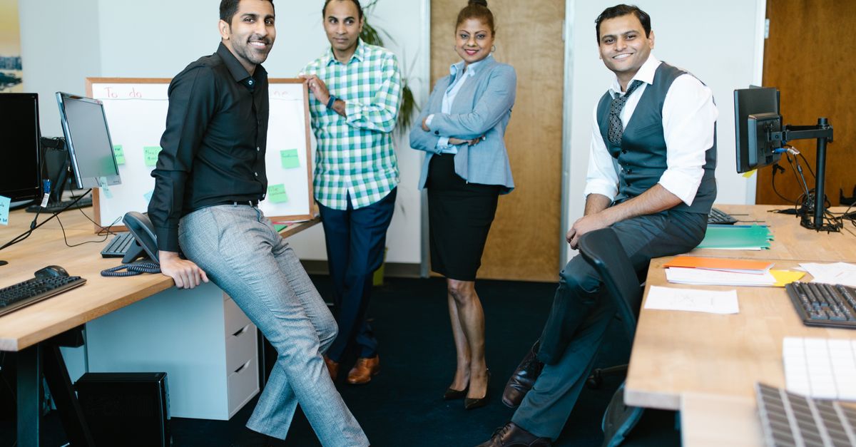 Group of happy business professionals posing together in a modern office setting.