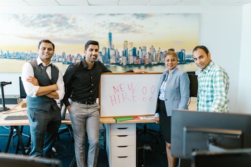 Free Diverse team standing with 'New Hire' sign, symbolizing collaboration and teamwork. Stock Photo