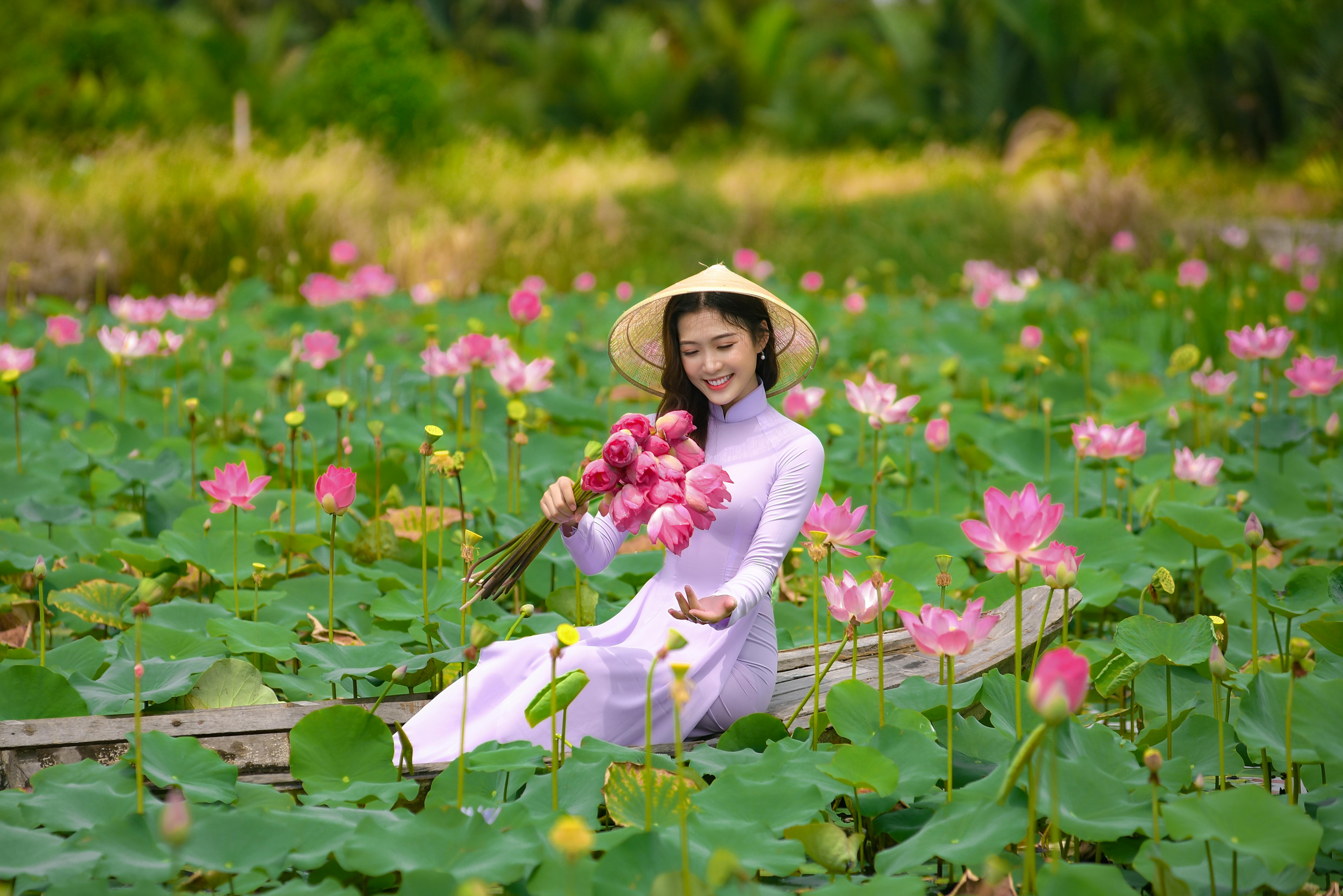 Woman in a White Dress Holding a Bunch of Pink Water Lilies · Free ...