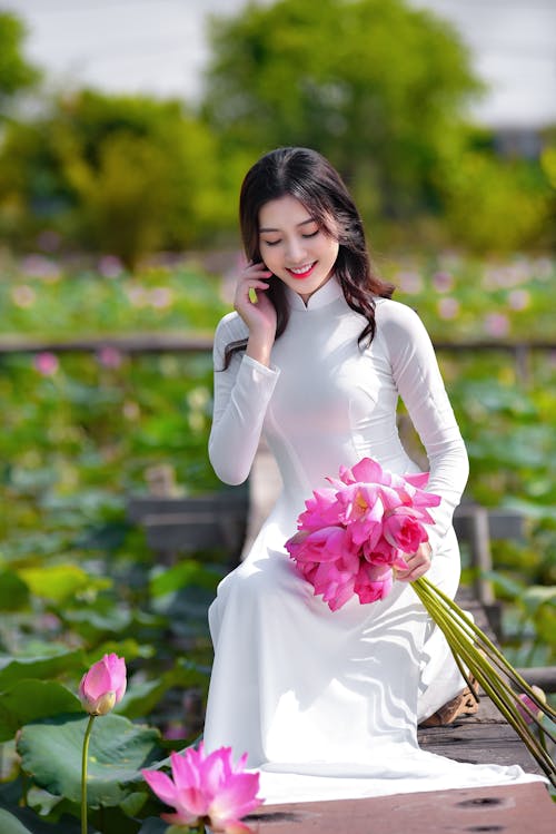 Woman in White Dress Holding Pink Flowers